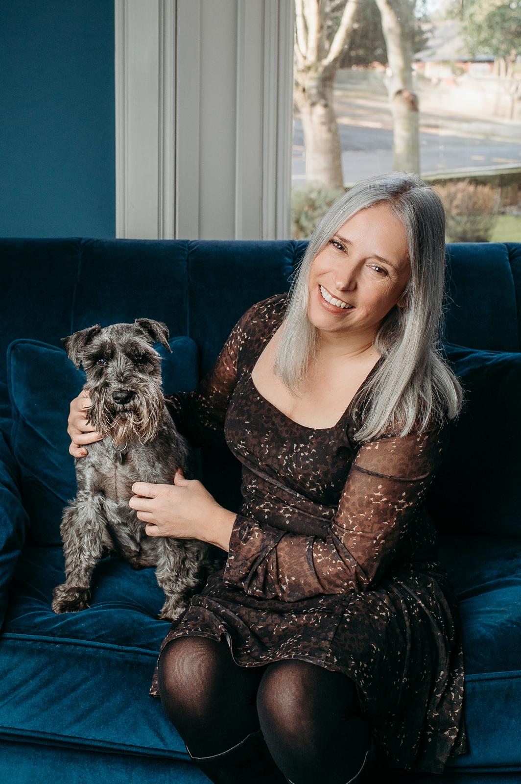 Marie on a blue velvet sofa with her grey schnauzer